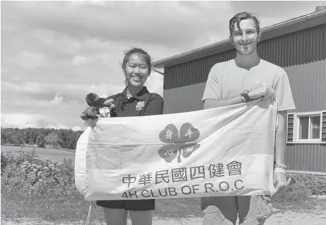  ?? [LIZ BEVAN / THE OBSERVER] ?? Ruby, or Hsu Ning Jui, and Andrew Grose from Alma pose with a Taiwanese 4-H flag at the Grose farm in Alma. The two participat­ed in an internatio­nal farming exchange with the 4-H Canada Going Global program.