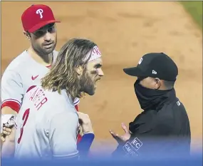  ?? JOHN MINCHILLO — THE ASSOCIATED PRESS ?? The Phillies’ Bryce Harper, front left, argues with umpire Roberto Ortiz, right, after Ortiz ejected Harper during the fifth inning against the New York Mets, Saturday.