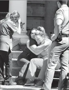  ?? Photograph­s by John Walker Associated Press ?? MEDICAL PERSONNEL comfort one another after being evacuated from the clinic where the shooting occurred. SWAT team members stormed the office.