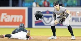  ?? MARTA LAVANDIER/AP ?? The Marlins’ Jazz Chisholm Jr. (2) advances to second base on an error on a pickoff throw to first as Pirates shortstop Kevin Newman waits for the throw Saturday.