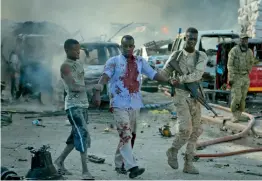  ?? — AP ?? A Somali soldier helps a civilian who was wounded in a blast in the capital of Mogadishu, Somalia, on Saturday. A huge explosion from a truck bomb has killed at least 20 people in Somalia's capital, police said on Saturday, as shaken residents called...