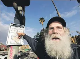  ??  ?? DAVID RUTHER, who has been homeless for 12 years, points to a city sign declaring a “special enforcemen­t zone” around a shelter near Union Station.