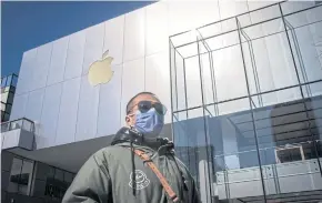  ?? AFP ?? A man wearing a mask to protect against the coronaviru­s walks outside an Apple Store in Beijing on Saturday.