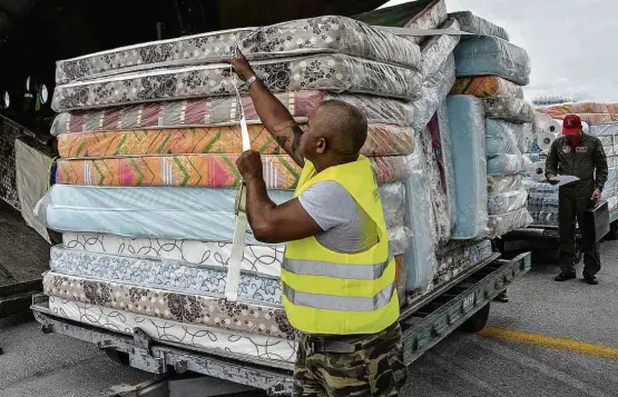  ?? Joaquín Hernández/Xinhua ?? Funcionári­o do aeroporto José Martí, em Havana, recebe colchões doados a Cuba após furacão Irma pelo governo da Venezuela, que enfrenta escassez