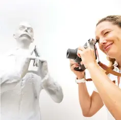  ??  ?? In this file photo taken on July 12, 2017 a staff of the Paris 2024 Olympic bid team takes a picture of a reproducti­on of a statue of Internatio­nal Olympic Committee (IOC) founder Pierre de Coubertin gesturing to make the form of the Eiffel tower,...