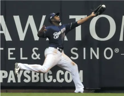  ?? AP PHOTO ?? Lorenzo Cain of the Milwaukee Brewers can’t quite haul in a ball hit by Chris Taylor of the Los Angeles Dodgers during the ninth inning of Game 1 of the National League Championsh­ip Series on Friday night in Milwaukee. The Brewers still prevailed, 6-5.