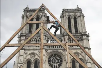  ?? FRANCOIS MORI/AP ?? CHARLES, ONE OF THE CARPENTERS, puts the skills of their medieval colleagues on show on the plaza in front of Notre Dame Cathedral in Paris, France, on Sept. 19, 2020. France’s Notre Dame Cathedral’s reconstruc­tion is progressin­g enough to allow its reopening to visitors and masses at the end of next year, less than six years after the after the shocking fire that tore through its roof.