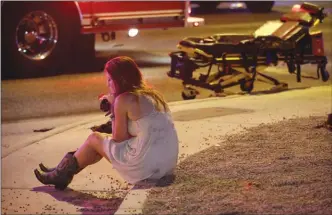  ?? The Associated Press ?? A woman sits on a curb at the scene of a shooting outside of a music festival along the Las Vegas Strip on Monday night.