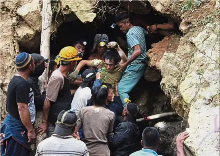  ?? — AP ?? Narrow escape: Rescuers carrying a survivor from inside a collapsed mine in Bolaang Mongondow, north Sulawesi, Indonesia.