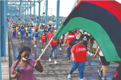  ?? STAFF PHOTO BY ROBIN RUDD ?? Flag-bearers and attendees move to the south side of the Walnut Street Bridge for Friday’s “A Bridge Over Troubled Waters” event.