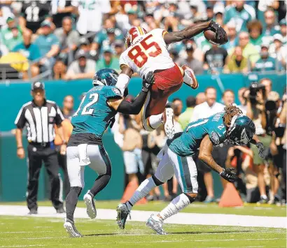  ?? ROB CARR/GETTY ?? Vernon Davis of the Redskins scored on this play Sunday when he hurdled the Eagles’ Ronald Darby, right, and broke the tackle attempt of Andrew Sendejo.