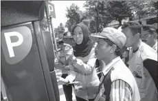  ?? DIPTA WAHYU/JAWA POS ?? BEGINI LHO PAK: Dwi Oktafiyah menjelaska­n kepada para juru parkir tentang penggunaan mesin parkir meter di Jalan Sedap Malam kemarin (9/1).