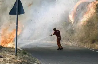  ?? FRANCESCO ARENA, THE ASSOCIATED PRESS ?? An Italian civil protection staffer tries to extinguish a fire in San Pietro in Guarano, southern Italy, Thursday.