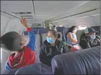  ??  ?? Yancarlos explores the instrument­s above his seat as his mother looks on during the airplane ride to Houston. Even though flying seems luxurious compared to her journey through Central America and Mexico and border detention, Ramirez was still anxious because it was her first time.