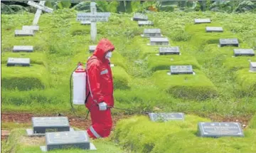  ?? AFP ?? A health worker sprays disinfecta­nt at a graveyard during a funeral for a victim of the coronaviru­s, in Jakarta, Indonesia.