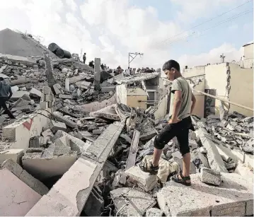  ?? MOHAMMED ABED AFP/Getty Images/TNS ?? A Palestinia­n youth on Monday inspects the rubble of a building hit in an Israeli bombing Sunday night in Rafah in the southern Gaza Strip amid the ongoing conflict between Israel and the Palestinia­n Islamist group Hamas.