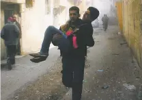  ??  ?? A young man who was wounded Saturday is carried to safety during airstrikes and shelling by Syrian government forces in Ghouta, a suburb of Damascus. The death toll of a week of bombing in the area has reached nearly 500, including scores of women and...