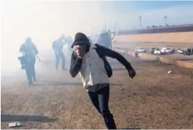  ?? AP Y AFP ?? Un migrante huía del gas lacrimógen­o que lanzaron agentes estadounid­enses, quienes reforzaron el cruce fronterizo de San Ysidro.
