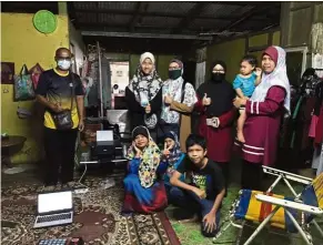  ??  ?? The gift of giving: (From left) Class teacher Mahadi Ab Aziz, Syahira, Nini, Azimah, Nurhayati and her other children posing with the gadgets.
