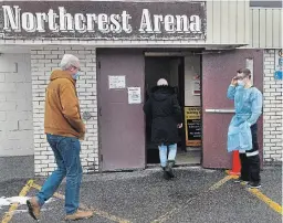  ?? CLIFFORD SKARSTEDT EXAMINER ?? A city paramedic opens the door for patients who have booked their appointmen­ts to get tested for COVID-19 at the Northcrest Arena on Tuesday.