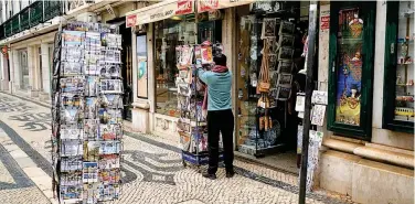  ?? File/reuters ?? ↑
A man organises newspapers in front of a store in Lisbon.