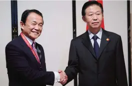  ??  ?? YOKOHAMA: China’s Finance Minister Xiao Jie (right) shakes hands with his Japanese counterpar­t Taro Aso during their meeting in Yokohama yesterday.