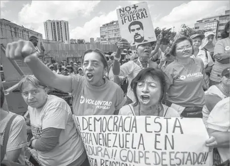  ?? Juan Barreto AFP/Getty Images ?? VENEZUELAN opposition activists rally in Caracas. The Supreme Court earlier in the week issued a pair of rulings that essentiall­y stripped the nation’s opposition-controlled legislativ­e branch of its powers, only to issue reversals in the face of...