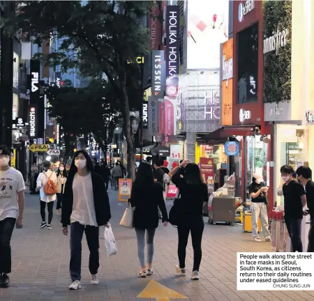  ?? CHUNG SUNG-JUN ?? People walk along the street in face masks in Seoul, South Korea, as citizens return to their daily routines under eased guidelines