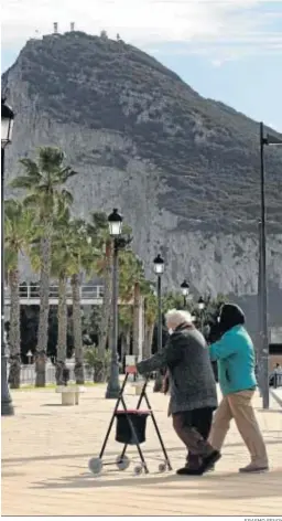  ?? ERASMO FENOY ?? Dos personas andan por La Línea con el Peñón de fondo.