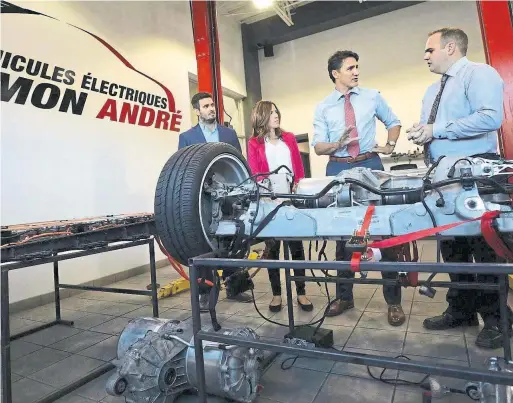  ?? INGENEXT ?? Prime Minister Justin Trudeau visits Véhicules électrique­s Simon André in Trois-Rivières, Que., an electric vehicle dealership owned by Simon André, right, and son Guillaume André, far left. Guillaume is president of Ingenext, which specialize­s in EV conversion­s. He bought two EVs, via online auction, that came with old batteries.