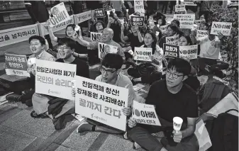  ?? Lee Jin-man / Associated Press ?? South Korean protesters in front of the Japanese Embassy in Seoul react to hearing their government will end the General Security of Military Informatio­n Agreement with Tokyo.