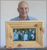  ?? (AP/Peter Meecham) ?? Jonathan Manning holds a photo of his children and their partners at his home in Christchur­ch, New Zealand. Manning helped guide his teenage children through their grief after their mother, Donna Manning, was killed in an earthquake that devastated the city.