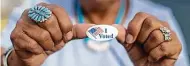  ?? Associated Press file photo ?? A voter shows off her sticker. Get yours, too.