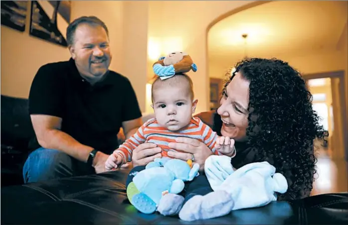  ?? CHRIS SWEDA/CHICAGO TRIBUNE ?? Angie and Mike Wall, both 43, play with their son, Nicholas, 6 months, at their home in Chicago’s Wrigleyvil­le neighborho­od last month.