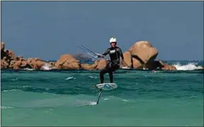  ??  ?? Chris Ballois tient la barre de son kitesurf avec une seule main.