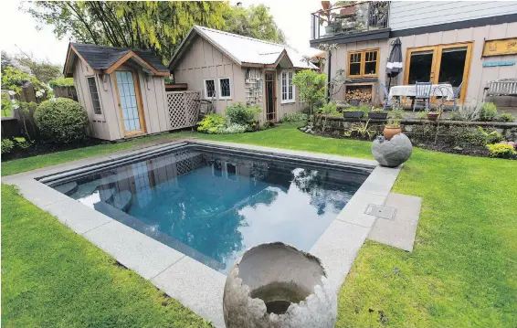  ??  ?? The pool, which is painted a dramatic black, was lifted over the house on a huge crane. Decorative orbs are by local artist Birgit Piskor. Terry LeBlanc removed interlocki­ng pavers from the edge of a terrace that stretches across the width of the house and filled the space with a selection of herbs.