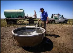  ?? DAVID GRAY — GETTY IMAGES FILE PHOTO ?? A farmer fills a drinking trough from a water truck for his cattle.