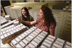  ?? (Arkansas Democrat-Gazette/Staci Vandagriff) ?? Chelsea Cinotto (left), an archival assistant, and Katie Adkins, project manager, go through boxed master microfilm negatives Friday in the cold storage at the Arkansas State Archives at One Capitol Mall in Little Rock.