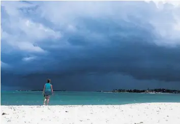  ?? ANDREW CABALLERO-REYNOLDS/GETTY-AFP ?? A woman walks on the beach in Nassau, Bahamas, on Thursday as a storm approaches. South Florida could see tropical storm force winds as early as Friday evening, with conditions improving by Saturday night.