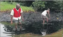  ?? AP FILE PHOTO ?? Men walk in an oil slick covering a creek near Bodo City in the oil-rich Niger Delta region of Nigeria in June 2010.