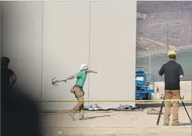  ??  ?? A MAN throws a grappling hook over a prototype to determine whether a person could climb over the wall. Many testers are part of Border Patrol’s tactical unit.