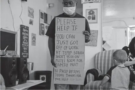  ?? AAron Ontiveroz, The Denver Post ?? Trye Taylor displays a hand-made sign in the unit that he was sharing with other people at the Summit View Inn on East Colfax Avenue in Aurora. Many residents stay there for months or years, often on the brink of homelessne­ss.