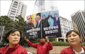  ?? AHN YOUNG-JOON / AP ?? An activist holds up a banner showing photos of North Korean leader Kim Jong Un with President Donald Trumpand South Korean President Moon Jae-in at a rally for peace Tuesday in front of the Singapore Embassy in Seoul, South Korea.
