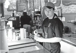  ?? STEVE LEBLANC/THE ASSOCIATED PRESS ?? Christophe­r Au, 19, dishes out ice cream at a J.P. Licks in Boston on Thursday. Au, who has worked at the shop for the past few months, said having a job helps him be more independen­t and not to have to rely on his parents too much for spending money.