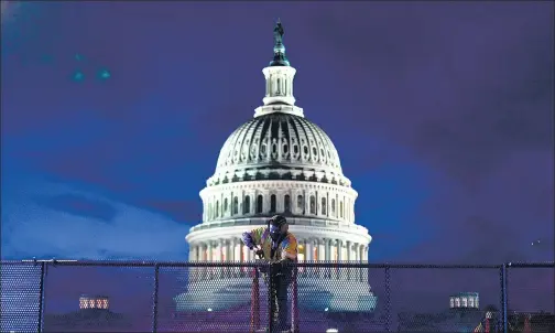  ?? REUTERS ?? A man installs heavy-duty security fencing around the US Capitol on Thursday, a day after supporters of outgoing President Donald Trump stormed the building.