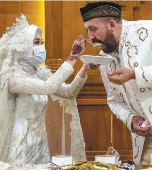  ??  ?? VIRUS CAN’T STOP US ... Indonesian bride Irra Chorina Octora feeds her Turkish husband Yavuz Ozdemir, while wearing a face mask during their wedding ceremony in Surabaya, Indonesia yesterday. – AFPPIX