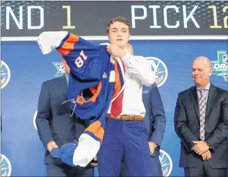  ?? AP PHOTO/MICHAEL AINSWORTH ?? Noah Dobson puts on a New York Islanders jersey after being selected by the team during the NHL Entry Draft in Dallas on Friday night.