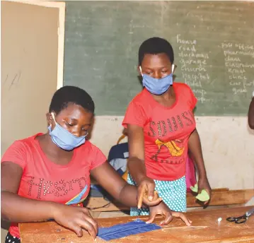  ??  ?? Some of the youths exchange notes on the reusable face mask making process