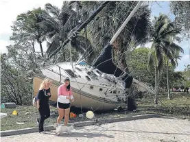  ??  ?? A boat lifted from the sea and dumped on land by huge waves in Florida