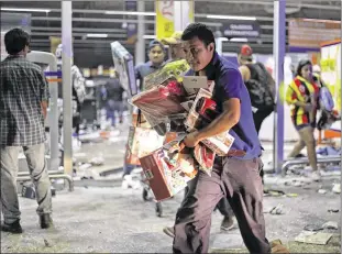  ?? ILSE HUESCA / AP ?? A man runs with toys Wednesday as a store is ransacked by a crowd in the port of Veracruz, Mexico. Store guards were overrun as protests over a sharp gasoline price hike erupted into looting of gas stations and stores in various parts of Mexico, including 50 businesses in the Gulf Coast city of Veracruz.